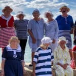 A group of women and men dressed up in victorian beachwear