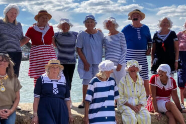 A group of women and men dressed up in victorian beachwear