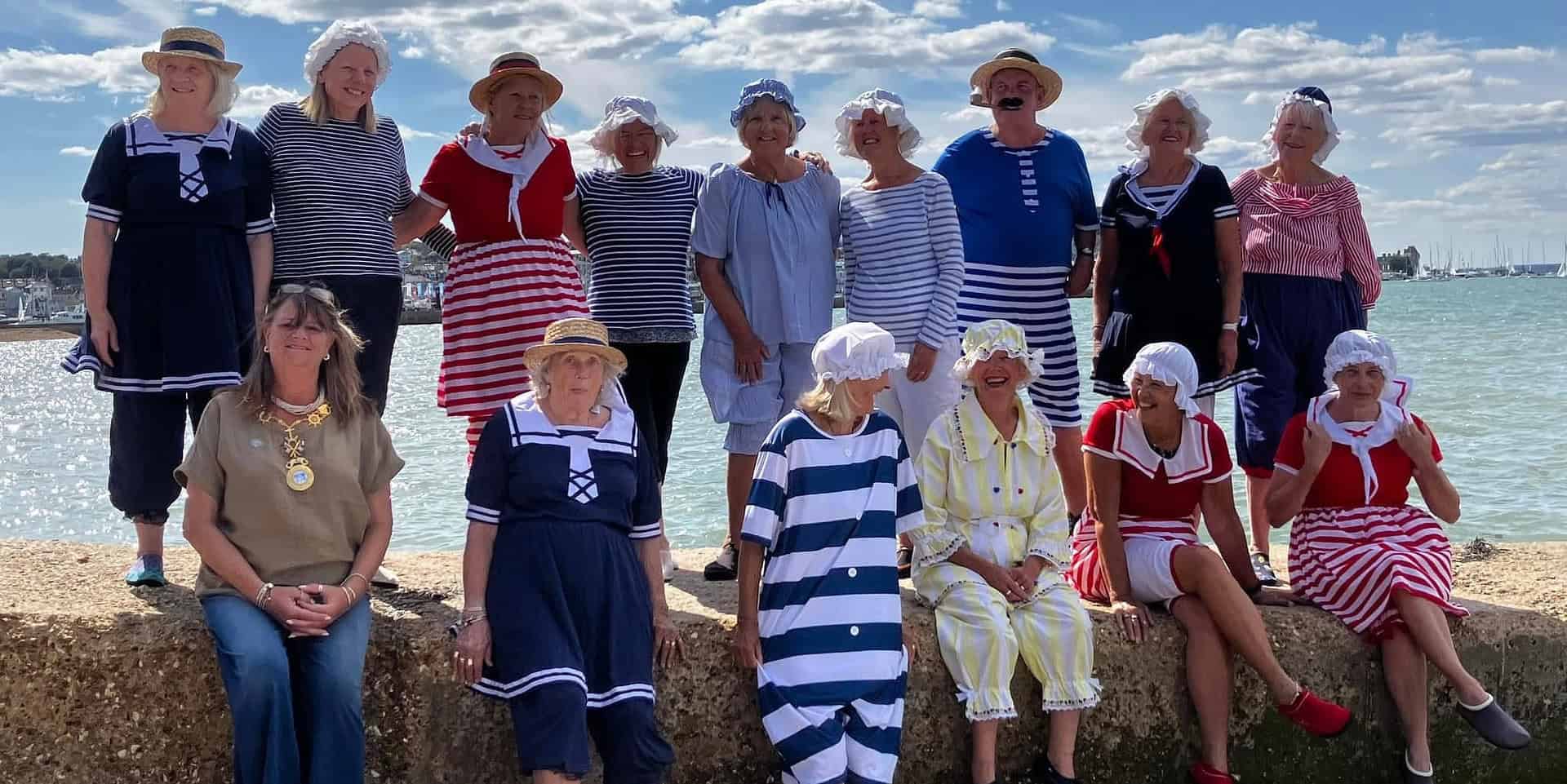 A group of women and men dressed up in victorian beachwear