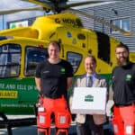 Founder of Ahmad tea in front of air ambulance with crew and large box of tea
