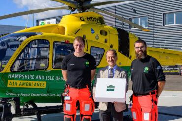 Founder of Ahmad tea in front of air ambulance with crew and large box of tea