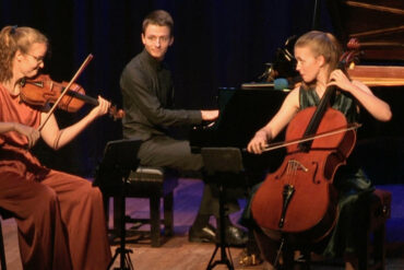 Amelio Trio playing instruments on stage