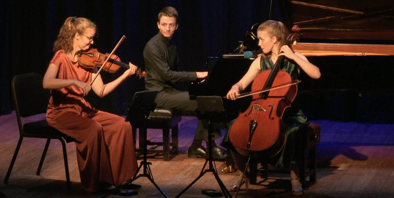 Amelio Trio playing instruments on stage