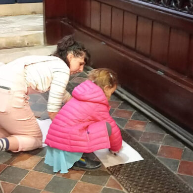 Mother and child doing frottage rubbings of the metal grills on the floor