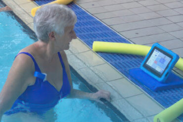 Woman in swimming pool reading instructions from waterproof tablet