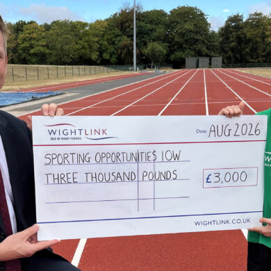 Jake holding a giant cheque with Steve Exley on the running track