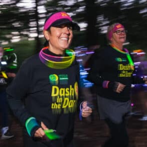 Runners dressed in Dash in the Dark tops running through a park