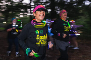 Runners dressed in Dash in the Dark tops running through a park