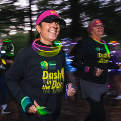 Runners dressed in Dash in the Dark tops running through a park