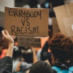 anti-racism protest with protestor holding placard that reads 'everybody vs racism'