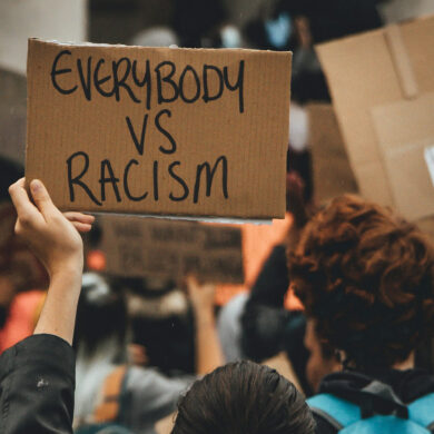 anti-racism protest with protestor holding placard that reads 'everybody vs racism'