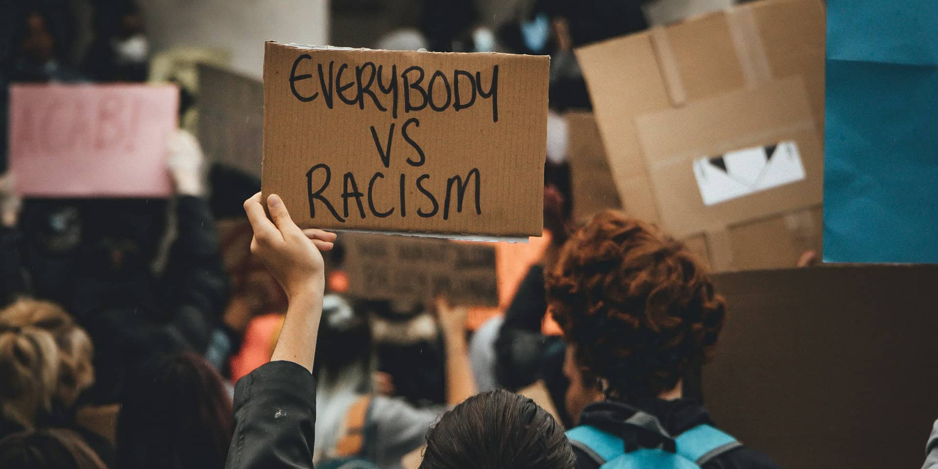 anti-racism protest with protestor holding placard that reads 'everybody vs racism'