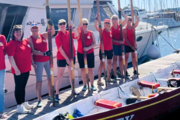 Gig rowers standing on the pontoon next to their gig all holding their oars