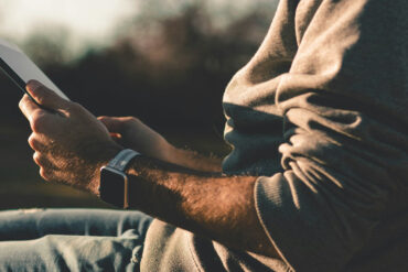 man sitting outside holding an ipad in his hands