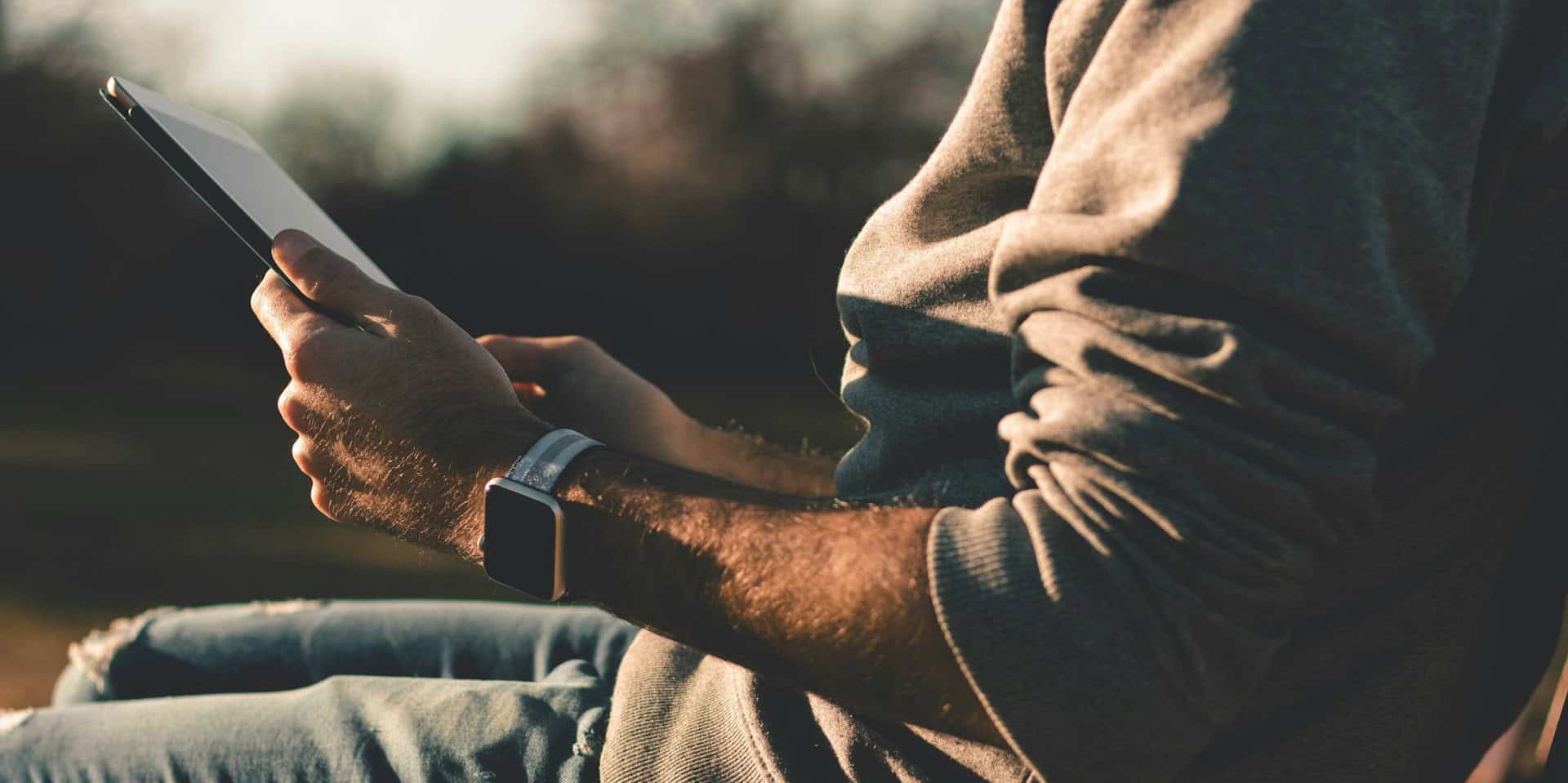 man sitting outside holding an ipad in his hands