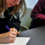 people sitting at a desk writing on paper