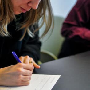 people sitting at a desk writing on paper