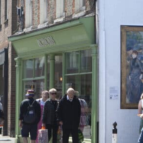 People looking at a reproduction of a National Gallery painting on the side wall of a shop in Newport