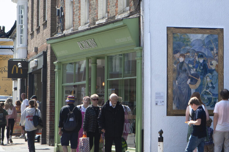 People looking at a reproduction of a National Gallery painting on the side wall of a shop in Newport