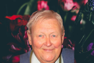 Bouquet of flowers on a dark background with photo of Ken Matthews on top