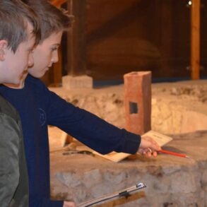 Two boys at newport roman villa with a clipboard and pointing at exhibits