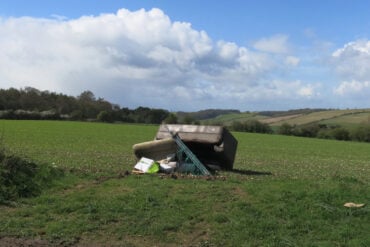 Sofa and other rubbish fly-tipped in a field