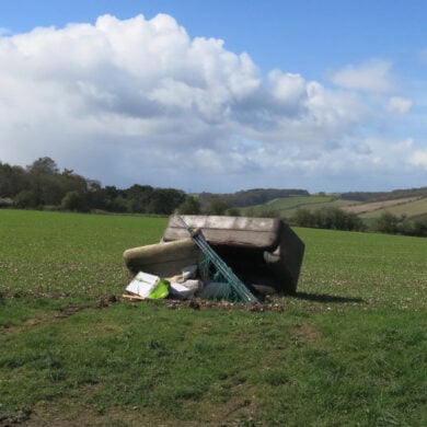 Sofa and other rubbish fly-tipped in a field
