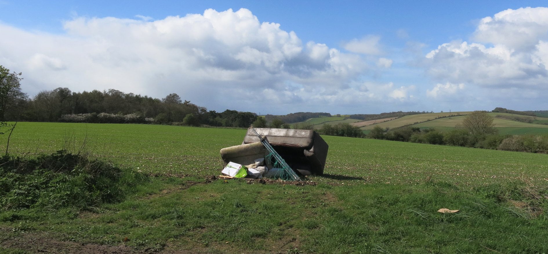 Sofa and other rubbish fly-tipped in a field
