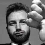 Black and white photo of a man in a suit gesturing thumbs down