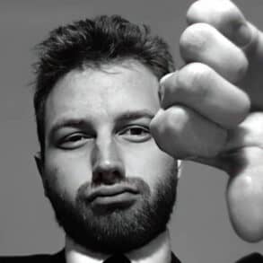 Black and white photo of a man in a suit gesturing thumbs down