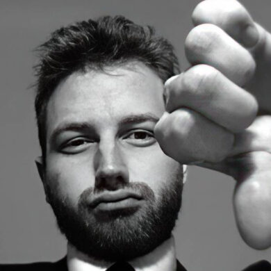 Black and white photo of a man in a suit gesturing thumbs down