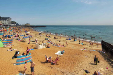Ventnor beach during the summer with lots of people sunbathing and swimming