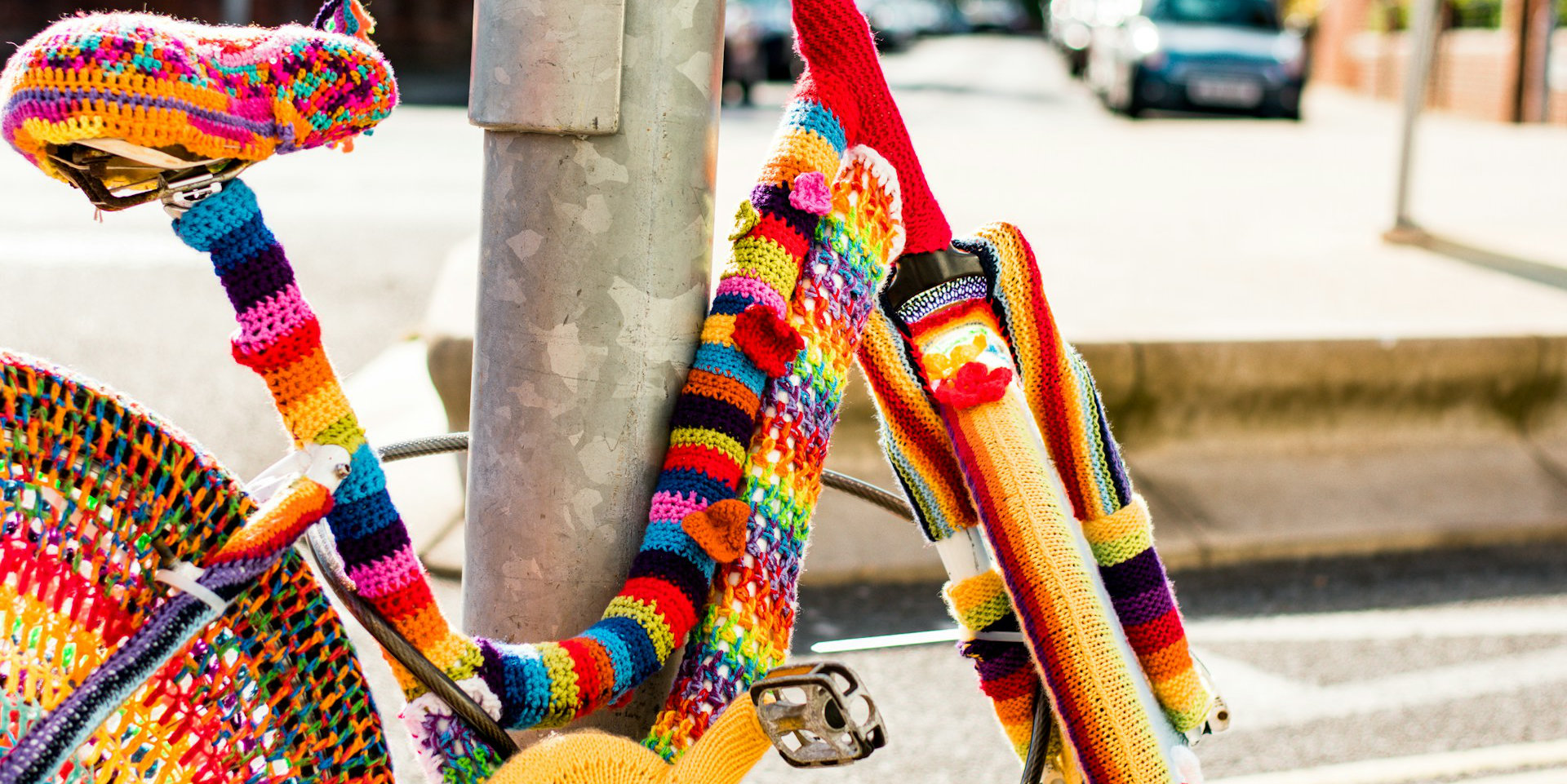 bicycle by a lamp post that has been covered in knitting
