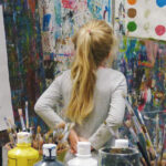 child in artists studio looking at painted colour dots