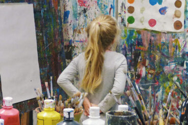 child in artists studio looking at painted colour dots