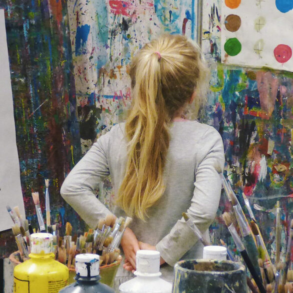 child in artists studio looking at painted colour dots