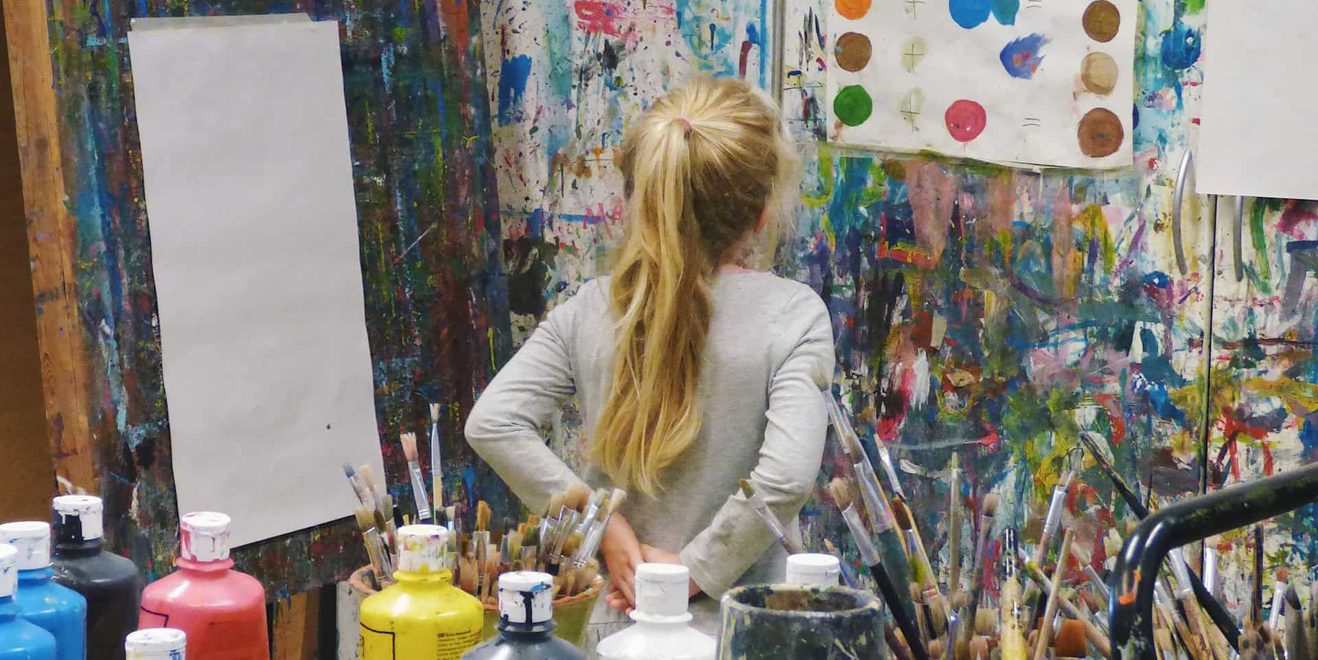child in artists studio looking at painted colour dots