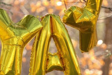 gold letter balloons spelling YAY
