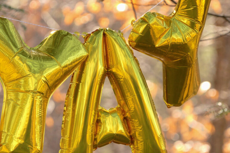 gold letter balloons spelling YAY