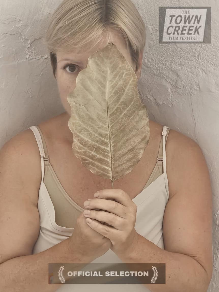 image showing woman holding large leaf in front of her face