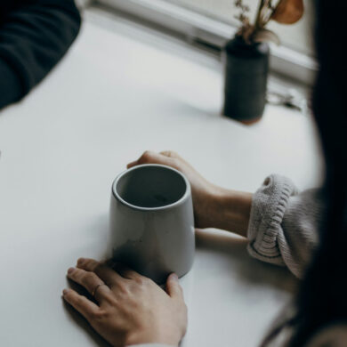 two people sitting at a table with cups of coffee or tea