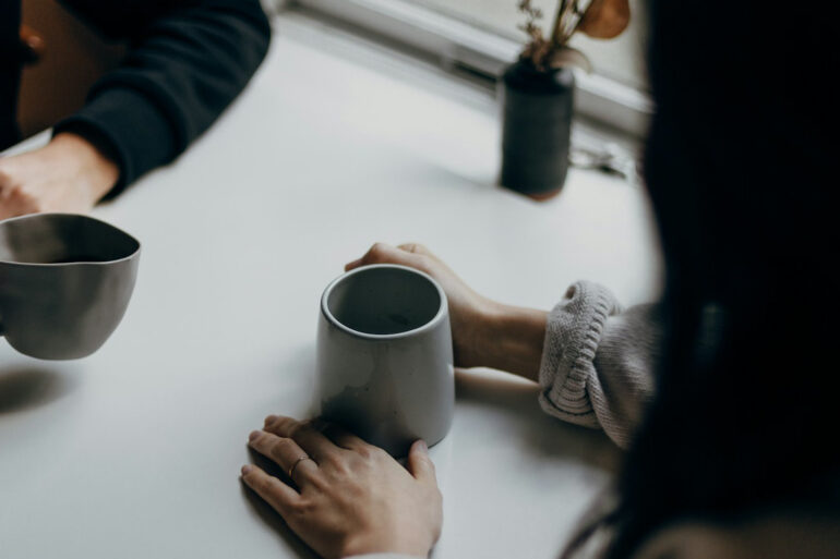 two people sitting at a table with cups of coffee or tea